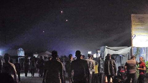 فلسطينيون في رفح، جنوب قطاع غزة، يشاهدون اعتراض مقذوفات أُطلقت من إيران باتجاه إسرائيل في 13 يونيو/حزيران 2025.