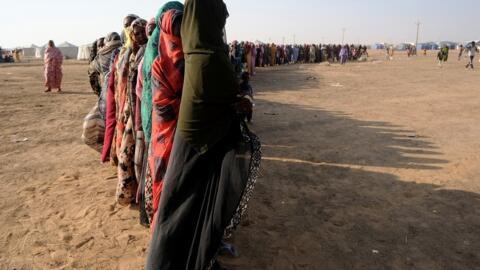 نازحات سودانيات يقفن في طابور طويل للحصول على إمدادات غذائية في مخيم للنازحين في الدبة، السودان، 13 نوفمبر/تشرين الثاني 2025