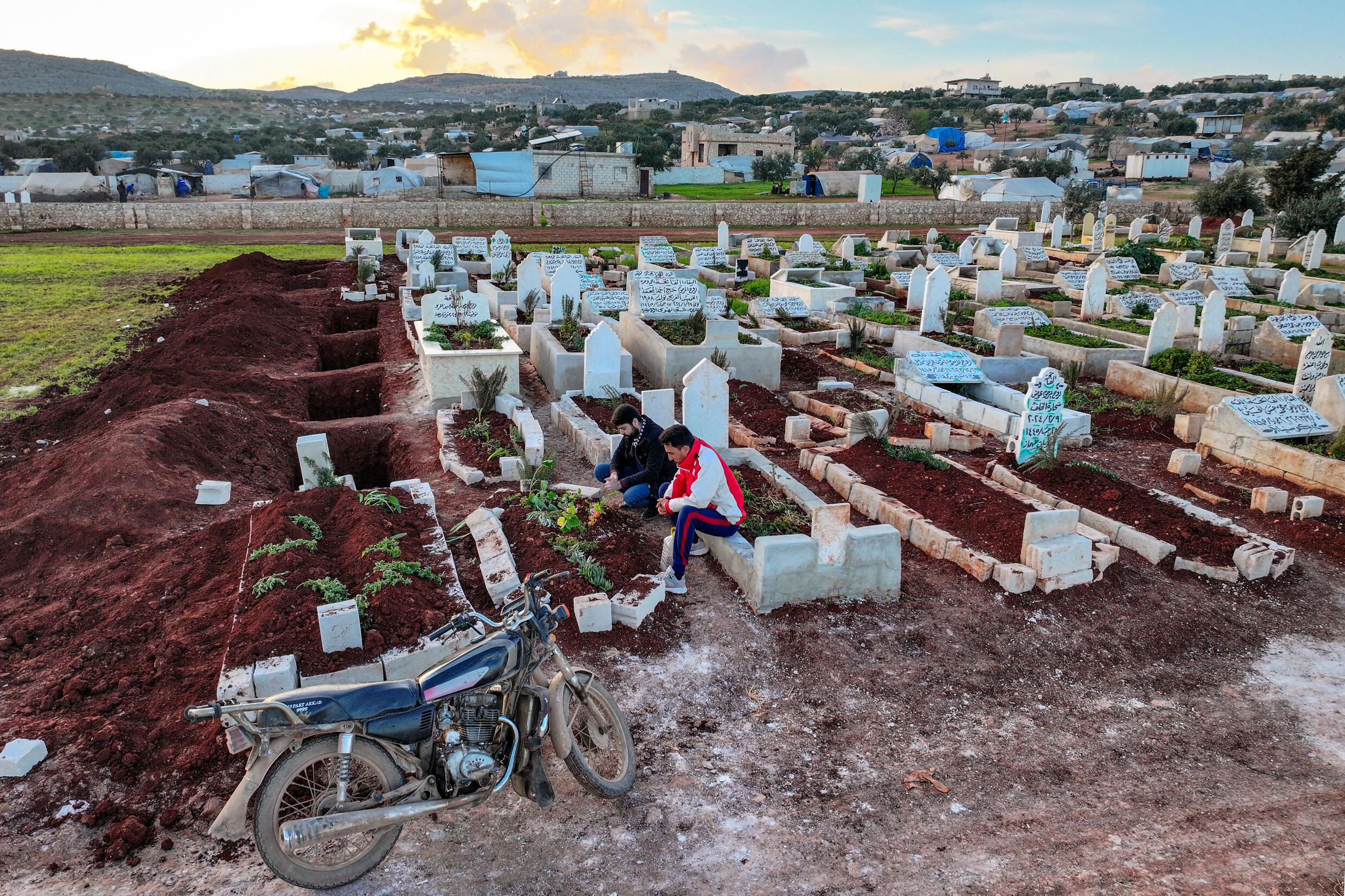 أحمد الحكيم (يسار) عند قبر شقيقه عبد القادر الذي قضى تحت التعذيب في سجن تابع لهيئة تحرير الشام، في بلدة حربنوش بمحافظة إدلب في شمال غرب سوريا في 8 آذار/مارس 2024