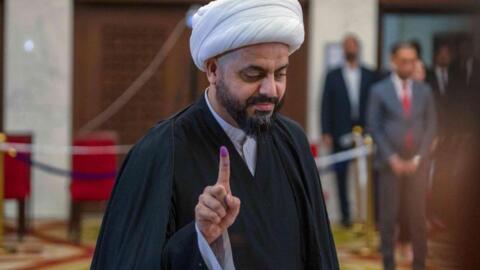 رئيس عصائب أهل الحق العراقي قيس الخزعلي يُظهر إصبعه ملطخا بالحبر بعد الإدلاء بصوته في مركز اقتراع ببغداد