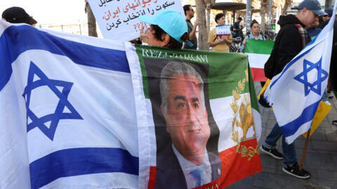 رفع الناس أعلامًا إسرائيلية وعلم إيران ما قبل الثورة الإسلامية عام 1979، والذي يحمل صورة رضا بهلوي، نجل آخر شاه لإيران، محمد رضا بهلوي، خلال مظاهرة تضامنية مع المتظاهرين الإيرانيين في مدينة تل أبيب الساحلية في 16 يناير/كانون الثاني 2026.