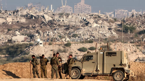 جنود من الجيش الإسرائيلي يقفون بجانب مركبة مدرعة في موقع على طول السياج الحدودي مع قطاع غزة جنوب إسرائيل، 12 سبتمبر/أيلول 2025.