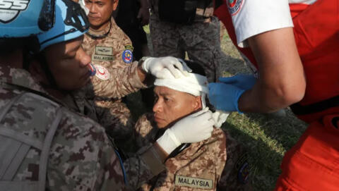صورة أرشيفية لمنقذ وعضو من الكتيبة الماليزية في قوات اليونيفيل يعالجان جرح زميل له، بعد إصابته في موقع غارة جوية إسرائيلية في صيدا، في 7 نوفمبر/تشرين الثاني 2024