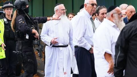 الحاخام دانيال ووكر (الثالث من اليسار) يقف بين ضباط شرطة يتحدثون إلى أفراد الجالية اليهودية خارج كنيس هيتون بارك التابع للطائفة العبرية في كرامبسال، شمال مانشستر، في 2 أكتوبر/تشرين الأول 2025، بعد هجوم على الكنيس