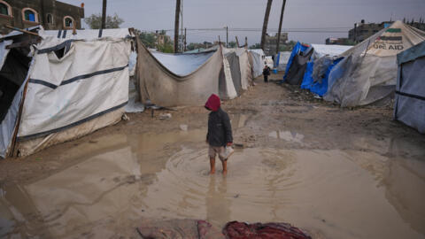 طفل فلسطيني في مخيم خيام مؤقت بعد هطول أمطار غزيرة، في دير البلح بوسط قطاع غزة،  الجمعة 12 ديسمبر/كانون الثاني 2025.
