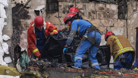 Rescuers put remains of a body of a victim into a plastic bag after Russian drone hit a multi-storey apartment building during massive missile and drone attack in Kyiv, Ukraine, Saturday, Dec. 27, 202