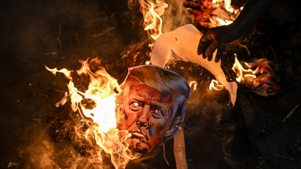 Activists of different trade unions burn an effigy of US President Donald Trump to protest against the recent tariff hikes imposed by the US on India during a demonstration in Kolkata on August 13, 20
